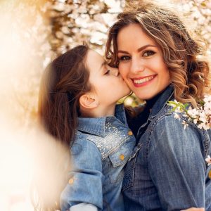 Fashionable mother with daughter. Family in a spring park. Woman in a blue shirt